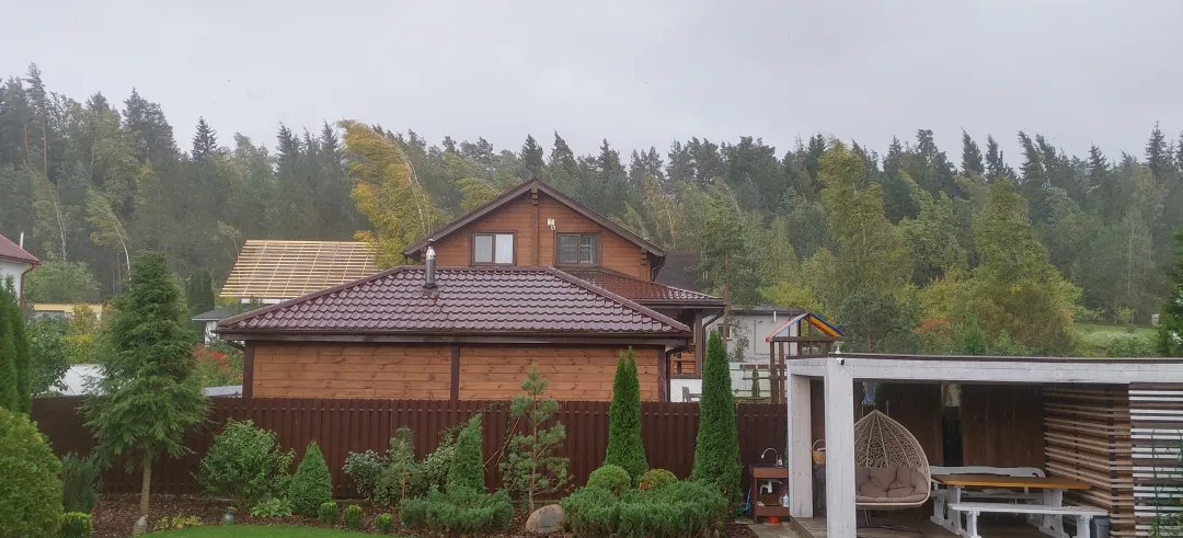 Casa rodeada de árboles con temporal de viento fuerte