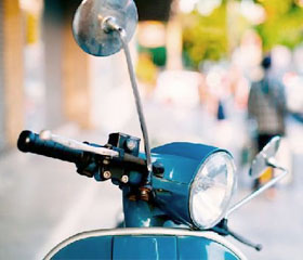 Moto tipo vespa aparcada en la acera